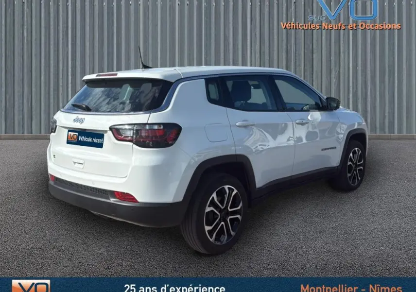 Jeep Compass blanc en vue 3/4 arrière droit, avec jantes alliage 18 pouces et vitres teintées.