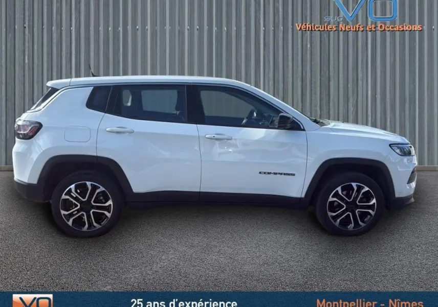 Vue latérale droite d'un Jeep Compass blanc 2024 avec jantes alliage 18 pouces et logo distinctif sur la porte