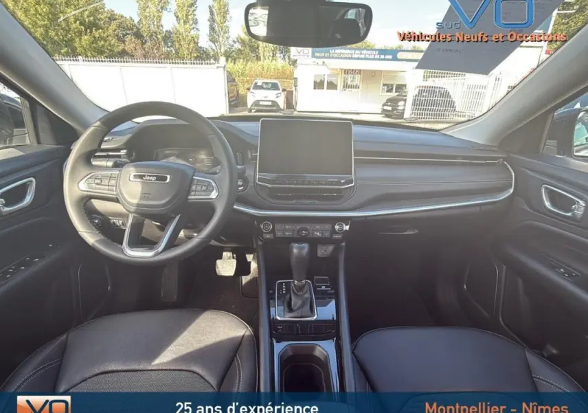 Vue intérieure avant du Jeep Compass 2024 avec tableau de bord noir et écran tactile central.