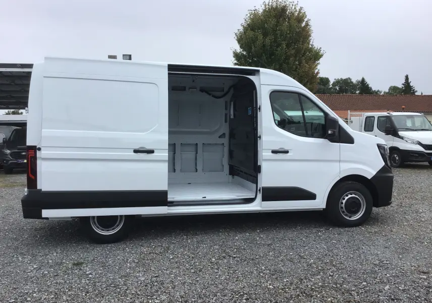Profil droit d’un Renault Master blanc 2025 avec porte latérale coulissante ouverte montrant l’espace de chargement vide.