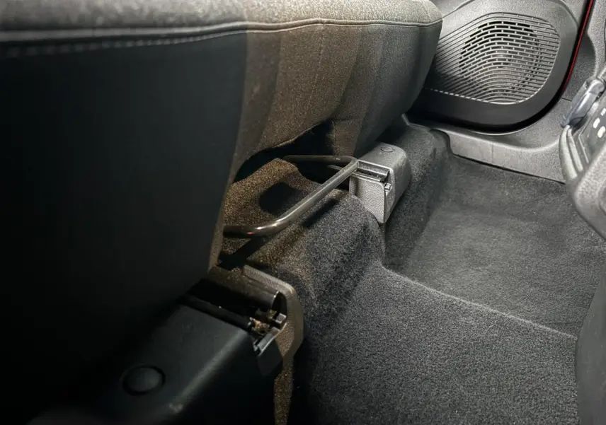 Vue rapprochée de l’espace pieds avant droit du Renault Captur 2025, moquette noire et enceinte de porte visible.