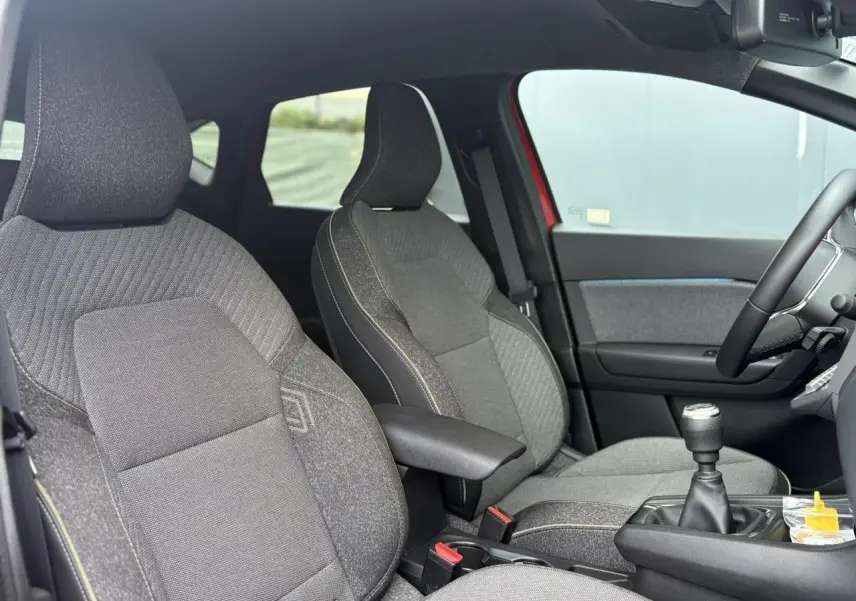 Vue intérieure côté droit du Renault Captur 2025, sièges gris avec surpiqûres jaunes et levier de vitesses manuel.