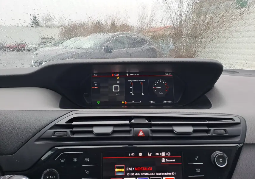 Vue intérieure du tableau de bord noir de la Citroën C4 Spacetourer blanche, avec affichage numérique et écran multimédia allumé.