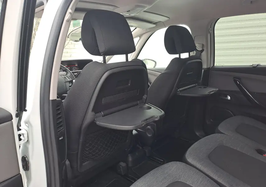 Vue intérieure arrière gauche du Citroën C4 Spacetourer blanc 2018, avec tablettes rabattables aux dossiers des sièges avant.