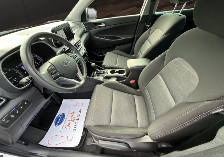 Vue intérieure côté conducteur du Hyundai Tucson 2020, sièges tissu noir et tableau de bord moderne.