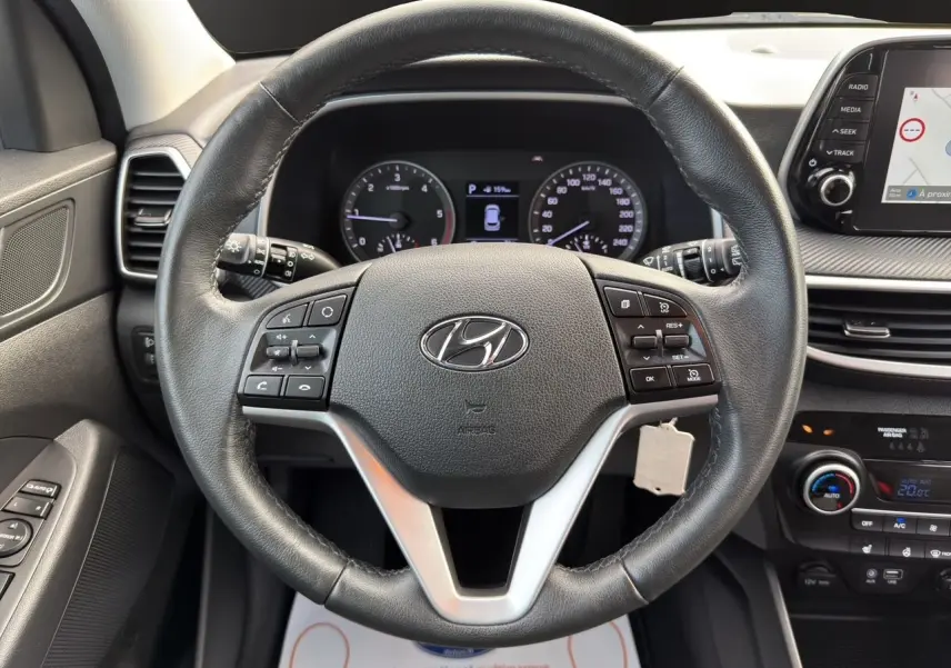Vue rapprochée du volant en cuir noir d’un Hyundai Tucson 2020 avec commandes intégrées et tableau de bord numérique.