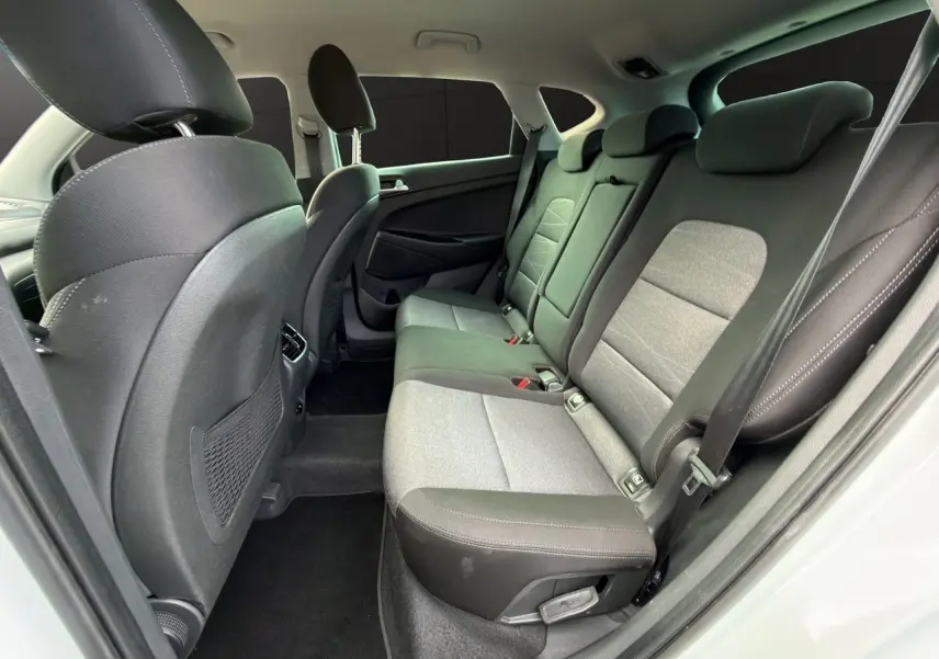 Vue intérieure côté droit montrant la banquette arrière en tissu noir et gris du Hyundai Tucson blanc polar 2020.