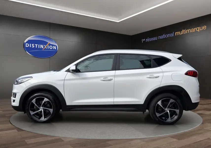 Vue de profil côté gauche du Hyundai Tucson blanc polar 2020 avec jantes 18 pouces bicolores et détails noirs contrastants.