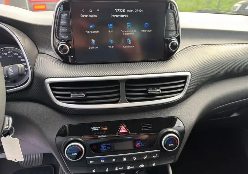Vue intérieure du tableau de bord du Hyundai Tucson blanc Polar 2020, avec écran tactile central et commandes de climatisation.