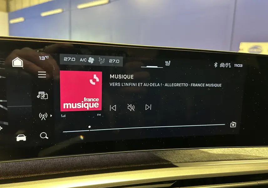 Écran tactile central du Peugeot 3008 Hybrid 2025 affichant la radio France Musique et la climatisation à 27°C.