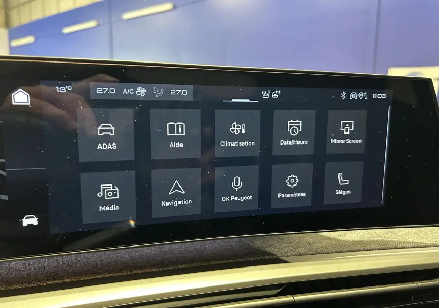 Écran tactile central du Peugeot 3008 hybride 2025 affichant les menus climatisation, navigation et aides à la conduite.