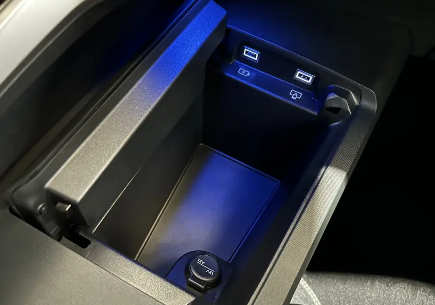 Vue rapprochée de la console centrale noire du Peugeot 3008 2025 avec ports USB et prise 12V éclairés en bleu.