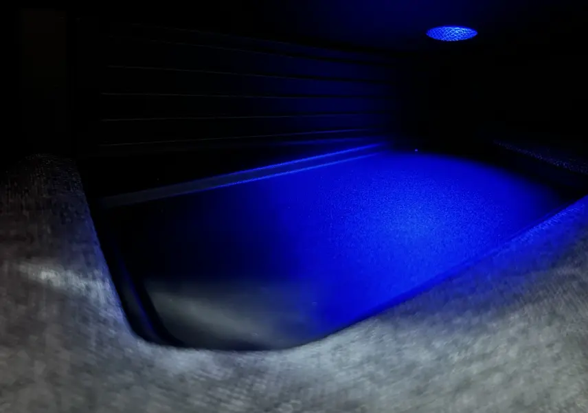 Gros plan sur l'éclairage d'ambiance bleu dans le compartiment de rangement intérieur du Peugeot 3008 blanc hybride.