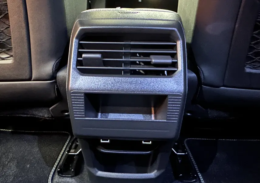 Vue rapprochée de la console arrière noire avec bouches d’aération et ports USB du Peugeot 3008 hybride blanc.