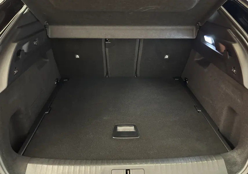 Coffre ouvert vu de l’arrière d’un Peugeot 3008 III Hybrid blanc, avec hayon électrique et intérieur noir.