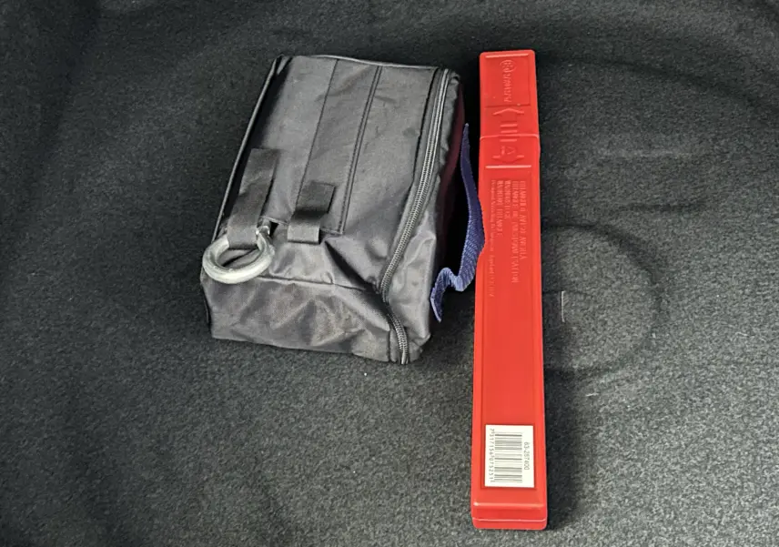 Coffre du Peugeot 3008 blanc Okenite avec sac noir et triangle de signalisation rouge posé à plat.