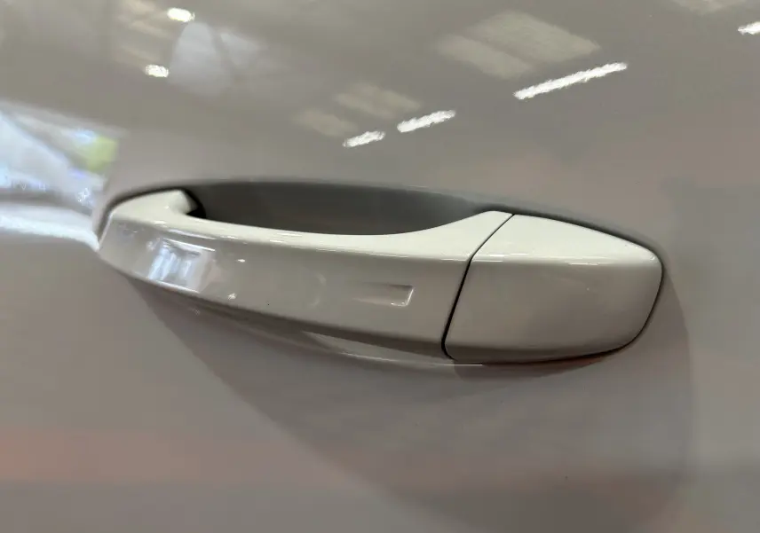 Poignée de porte blanche du côté gauche d'un Peugeot 3008 III Hybrid 145 e-DSC6 GT, finition lisse et brillante.