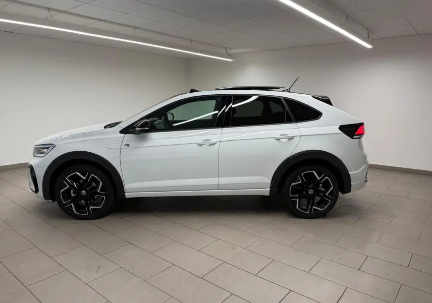 Vue de profil côté gauche d'un Volkswagen Taigo blanc pur avec toit noir et jantes alliage noires en intérieur neutre.