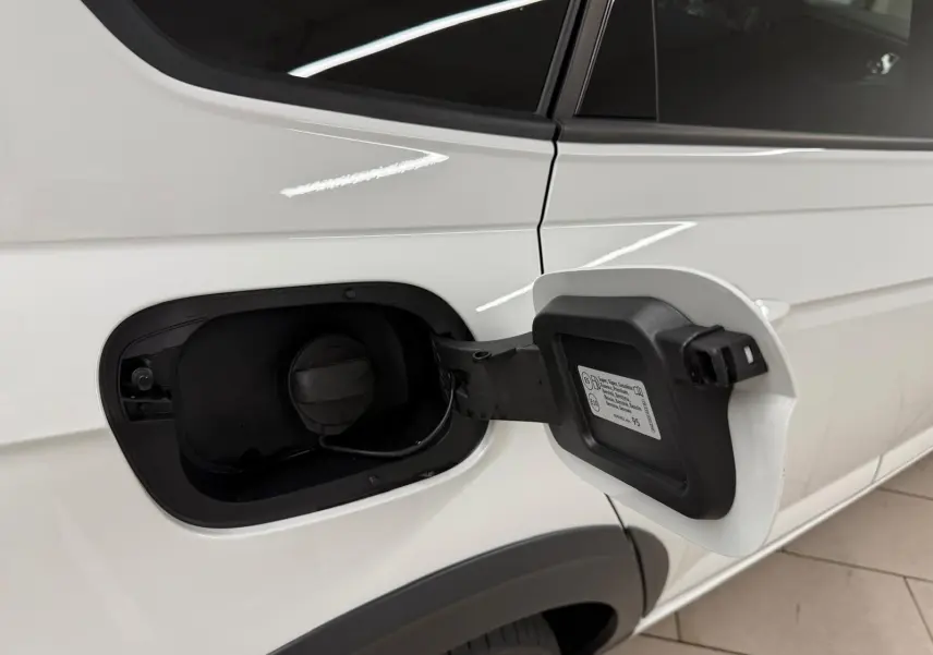 Vue rapprochée du côté gauche arrière d’un Volkswagen Taigo blanc pur avec trappe de carburant ouverte.