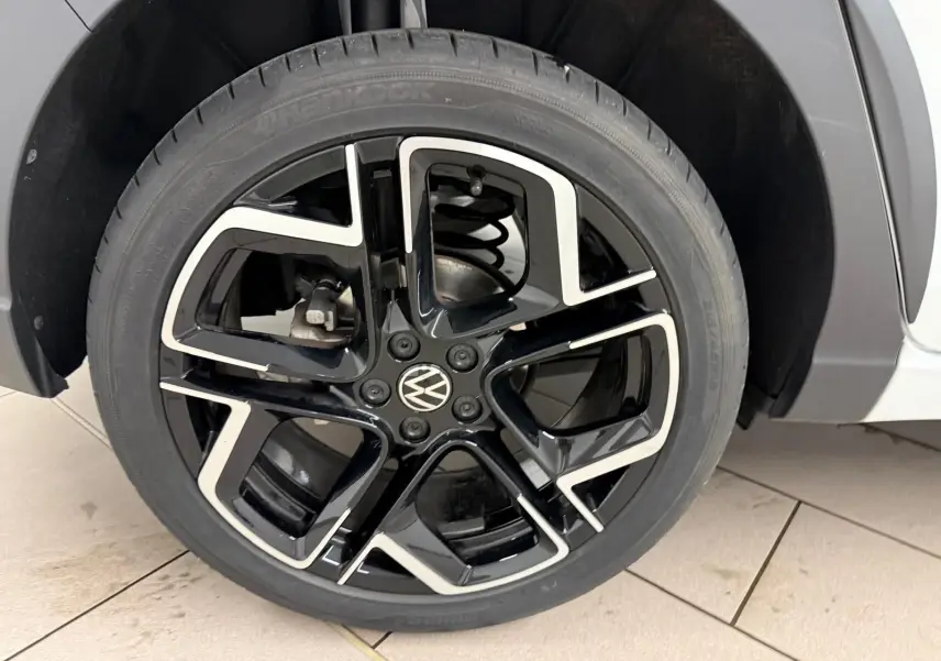 Gros plan sur la jante alliage noire et argentée 18 pouces du côté avant droit du Volkswagen Taigo blanc toit noir.