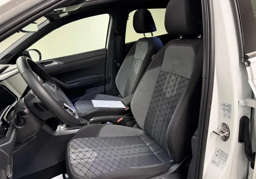 Vue intérieure côté conducteur du Volkswagen Taigo blanc, sièges sport en tissu noir et gris avec logo R-Line brodé.