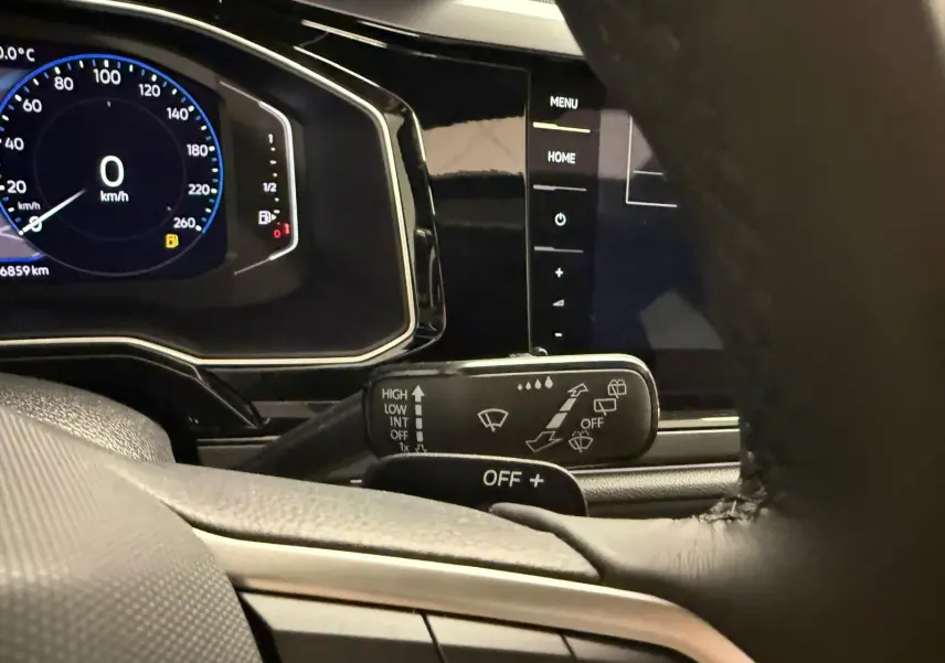 Vue rapprochée du tableau de bord et du commodo d'essuie-glace du Volkswagen Taigo 2025, intérieur noir.