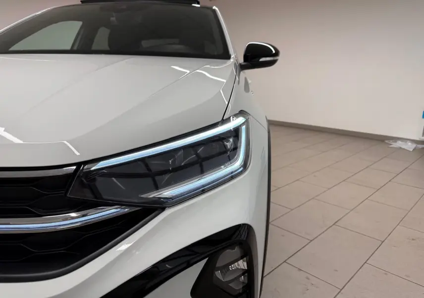 Gros plan sur l'avant droit du Volkswagen Taigo blanc pur avec projecteur Matrix LED et calandre noire.