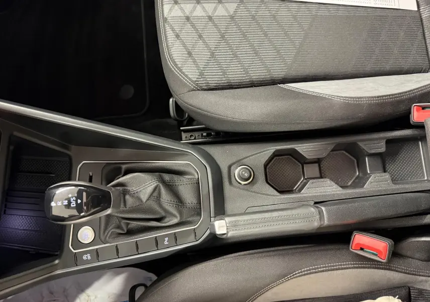 Vue plongeante sur la console centrale et levier de vitesse cuir d'une Volkswagen Taigo blanc pur toit noir.