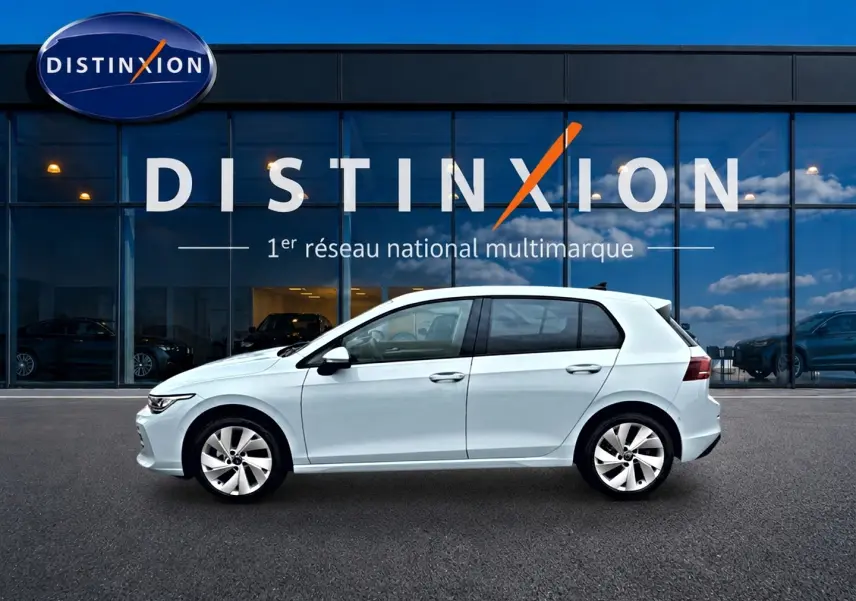 Profil côté gauche d'une Volkswagen Golf 1.5 etsi evo2 116 life dsg7 bleu glacier, garée devant une vitrine Distinxion.