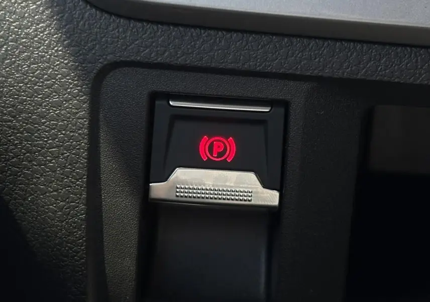 Gros plan sur le bouton de frein de stationnement électrique avec témoin rouge dans l'habitacle du Citroën Jumpy noir Perla.