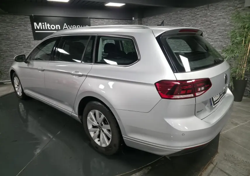 Vue 3/4 arrière droit d'une Volkswagen Passat SW gris métallisé en showroom avec feux arrière LED et jantes alliage.