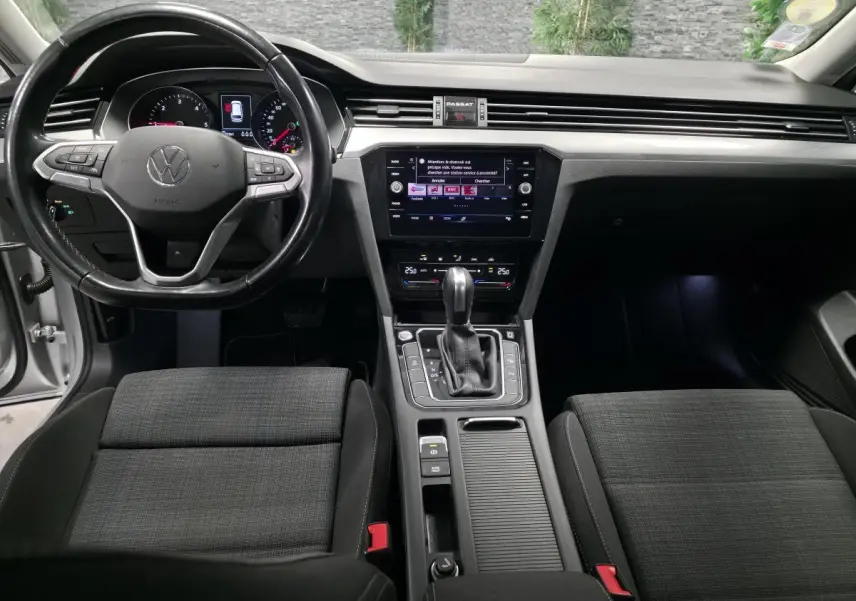 Intérieur avant de la Volkswagen Passat SW 2021, vue centrale sur tableau de bord et console, sièges tissu gris foncé.