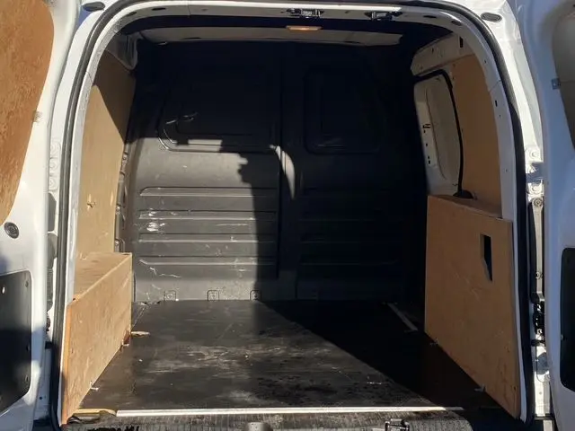Vue intérieure arrière du Renault Kangoo blanc 2023, version Van TCE 100 avec kit bois complet dans l’espace de chargement.
