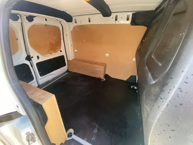 Vue intérieure arrière du Renault Kangoo blanc 2023, montrant l'aménagement bois complet du coffre utilitaire.