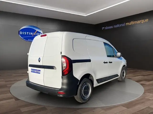 Vue 3/4 arrière droite d’un Renault Kangoo Van blanc avec kit bois, portes latérales et hayon fermé en showroom.