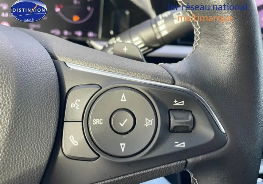 Gros plan sur les commandes audio et téléphone au volant cuir noir de l’Opel Grandland rouge hybride 2024.