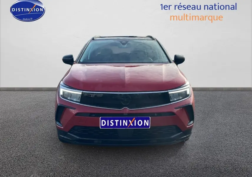 Vue frontale d'un Opel Grandland 1.6 turbo 225 hybride GS rouge métallisé avec calandre noire et phares LED.
