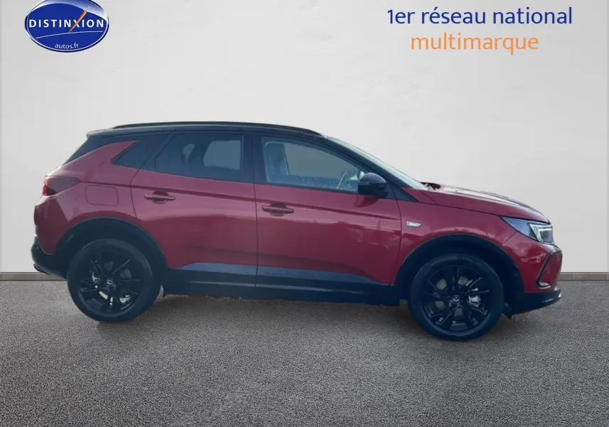 Opel Grandland hybride rechargeable rouge vu de profil côté gauche avec jantes noires et toit noir.