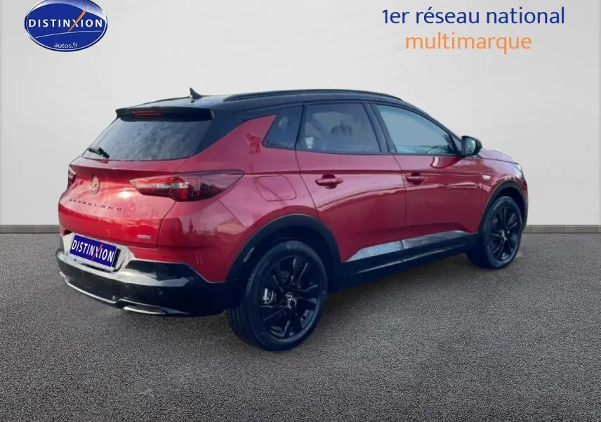 Vue 3/4 arrière droite d’un Opel Grandland rouge 2024 avec toit noir et jantes noires.