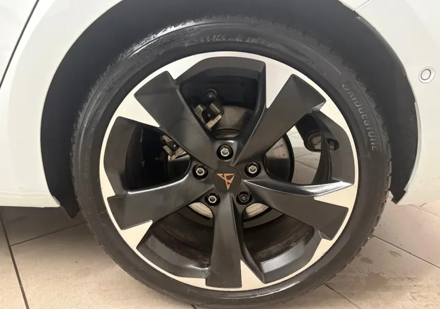 Gros plan sur la jante noire et argentée du côté avant droit d'une CUPRA Leon blanc Nevada, avec logo central distinctif.