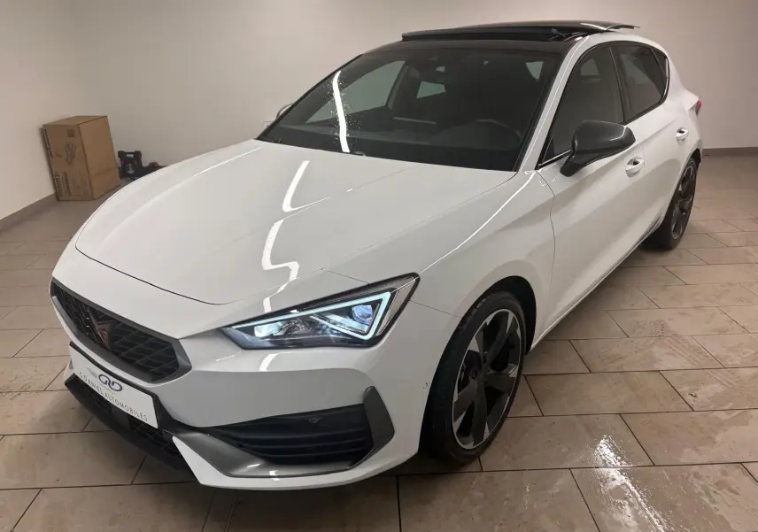 Vue 3/4 avant droite de la CUPRA Leon blanche Nevada avec toit ouvrant panoramique et jantes noires en intérieur.