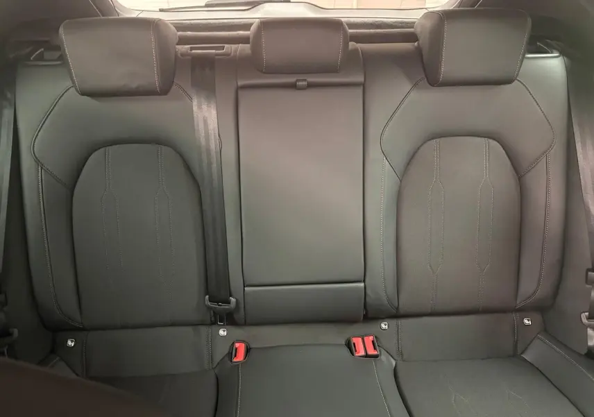 Vue intérieure des sièges arrière en cuir noir avec appuie-têtes et ceinture de sécurité centrale visible.