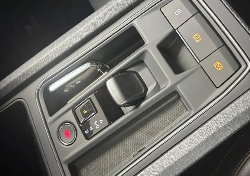 Vue rapprochée de la console centrale de la CUPRA Leon 2024, avec levier de vitesse compact et bouton de démarrage rouge.