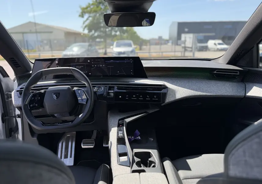 Intérieur du Peugeot 5008 Hybrid 145 GT 2025 vu de face, tableau de bord moderne avec écran large et volant compact noir.
