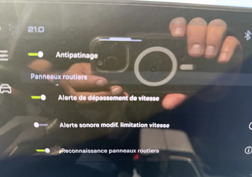 Écran tactile intérieur du Peugeot 5008 Hybrid 145 GT, affichant les réglages d’aide à la conduite avec reflet de mains.