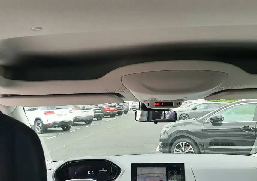 Vue intérieure avant du Peugeot Rifter bleu Kiama 2026, avec tableau de bord numérique et écran de caméra de recul.