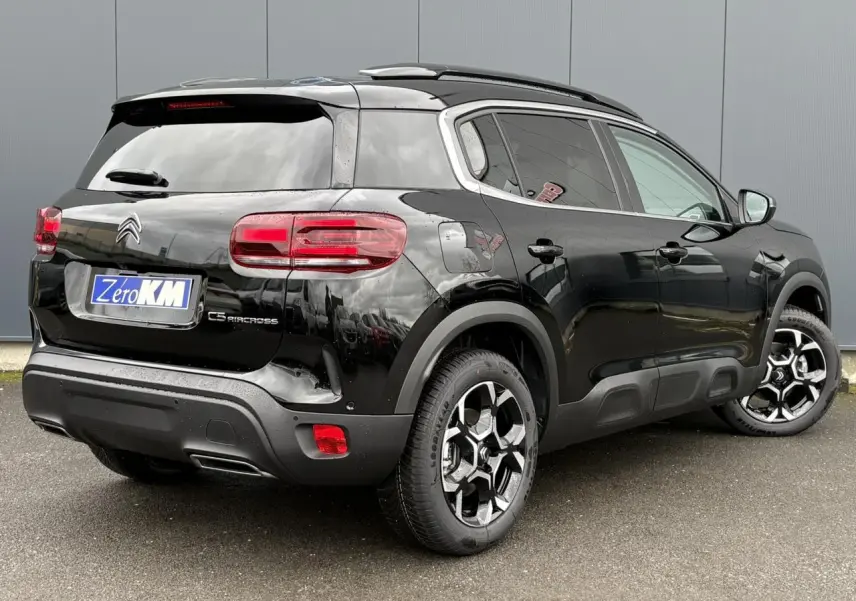 Vue 3/4 arrière droite du Citroën C5 Aircross noir Perla avec jantes alliage bi-ton et barres de toit noires.