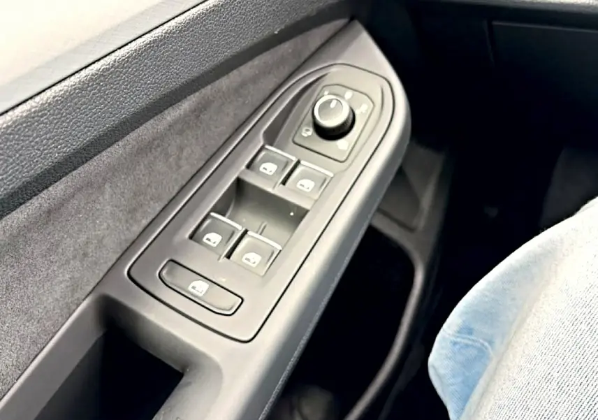 Gros plan sur la commande des vitres et rétroviseurs côté conducteur d’une Volkswagen Golf noire, intérieur gris.