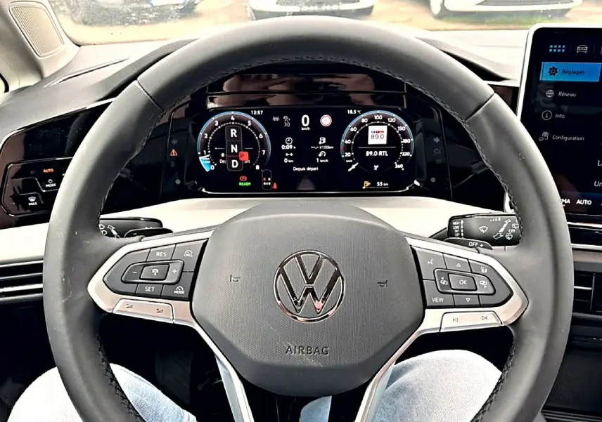 Vue intérieure centrée sur le volant noir de la Volkswagen Golf 2026 avec tableau de bord digital et commandes intégrées.