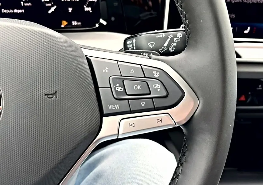 Gros plan sur le volant noir de la Volkswagen Golf 2026, montrant les commandes multifonctions côté droit.